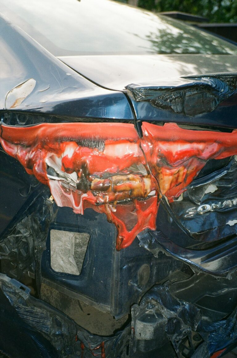 A person reviewing a car repair estimate with a vehicle and paperwork on a repair shop counter.