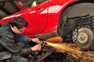A close-up of a mechanic's hands installing a new car part in a repair shop.